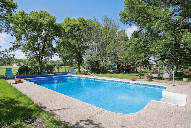 view of swimming pool with a covered pool, a yard, and fence