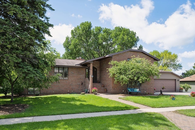 view of front of home with brick siding, a front lawn, driveway, an attached garage, and a chimney