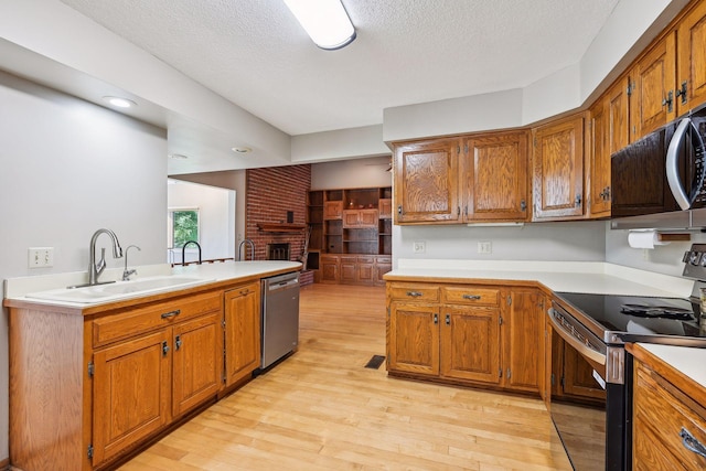 kitchen with stainless steel appliances, a sink, light countertops, brown cabinets, and a textured ceiling