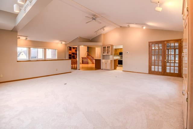 unfurnished living room with track lighting, lofted ceiling, baseboards, light carpet, and french doors