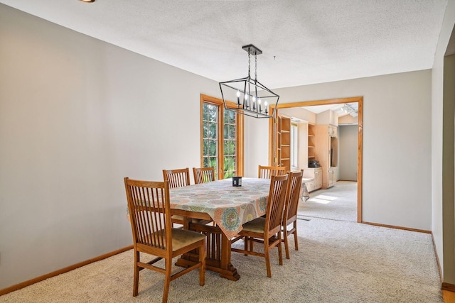 dining space featuring light colored carpet, a chandelier, baseboards, and a textured ceiling