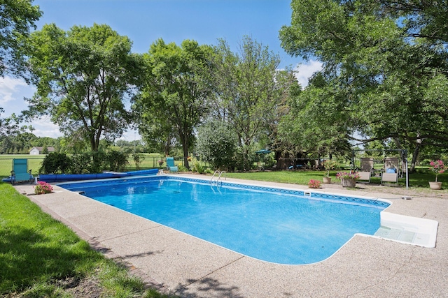 view of pool with a lawn and view of scattered trees
