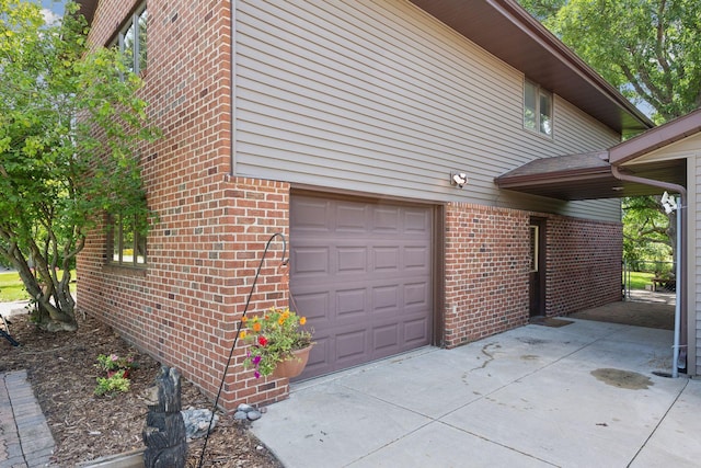 view of side of home featuring brick siding, an attached garage, and concrete driveway