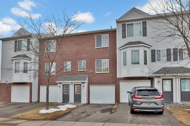 view of property featuring brick siding, an attached garage, and driveway