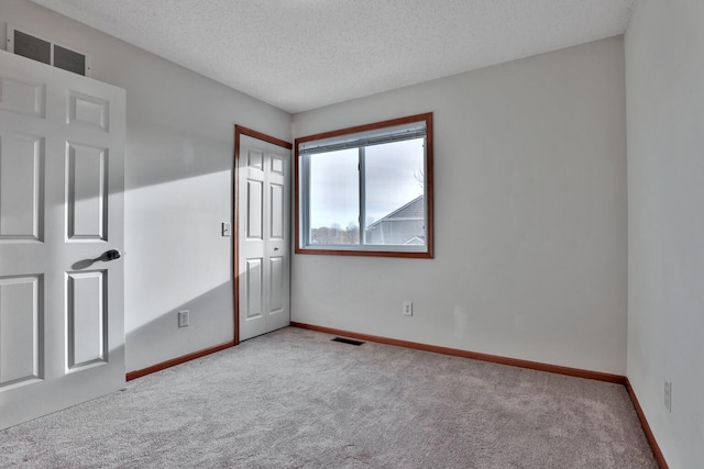 unfurnished bedroom with visible vents, baseboards, carpet, and a textured ceiling