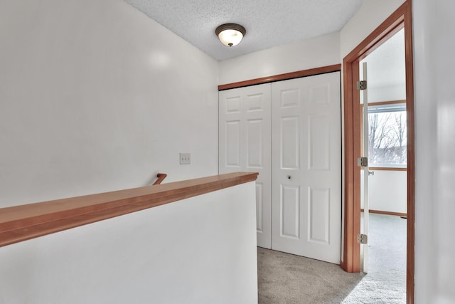 corridor featuring light carpet and a textured ceiling