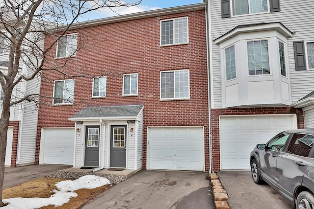 townhome / multi-family property featuring brick siding, driveway, and an attached garage