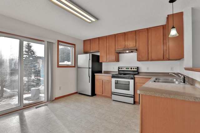 kitchen featuring visible vents, a sink, under cabinet range hood, stainless steel appliances, and light countertops