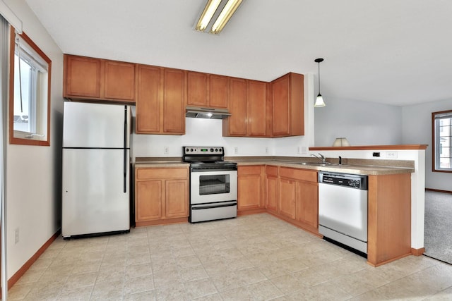 kitchen featuring under cabinet range hood, a peninsula, brown cabinetry, stainless steel appliances, and a sink