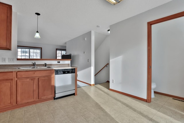 kitchen featuring baseboards, a sink, dishwasher, decorative light fixtures, and brown cabinets