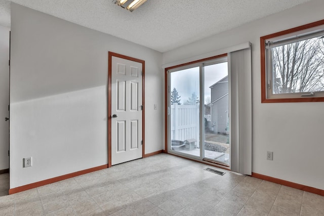 unfurnished room with visible vents, baseboards, and a textured ceiling