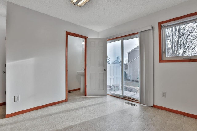 unfurnished room featuring visible vents, baseboards, and a textured ceiling