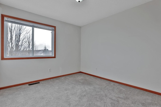 carpeted spare room featuring visible vents and baseboards