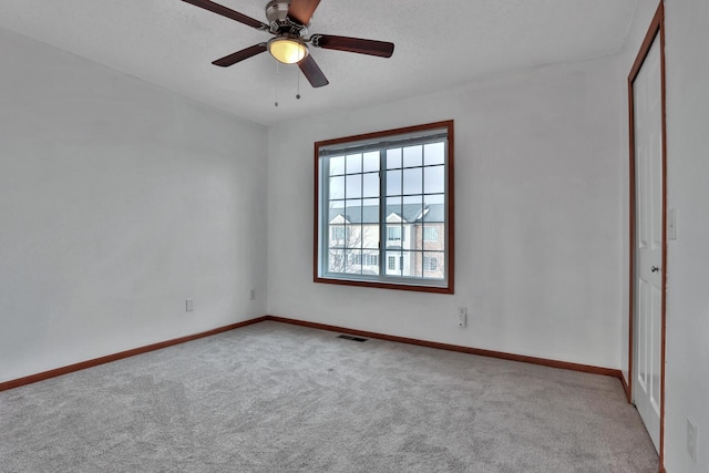 unfurnished room featuring ceiling fan, carpet, visible vents, and baseboards