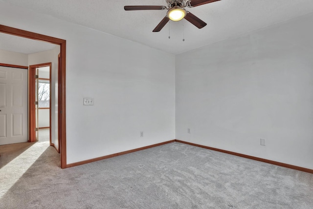 carpeted spare room with ceiling fan and baseboards