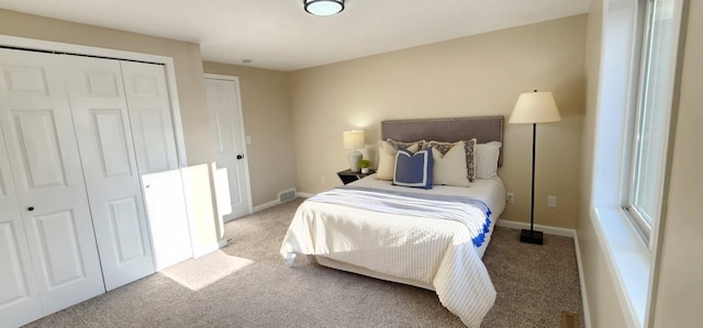 carpeted bedroom with a closet, visible vents, and baseboards