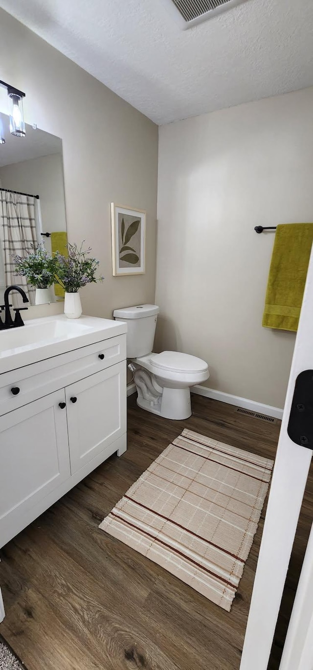 full bathroom with a textured ceiling, toilet, and wood finished floors