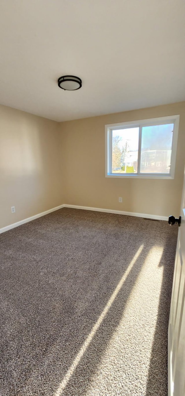 empty room featuring carpet and baseboards