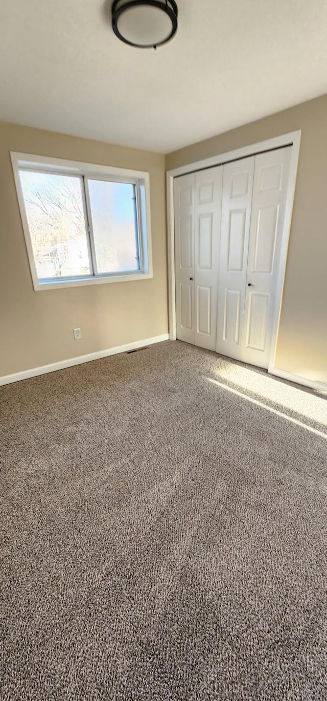 unfurnished bedroom with a closet, carpet, and baseboards