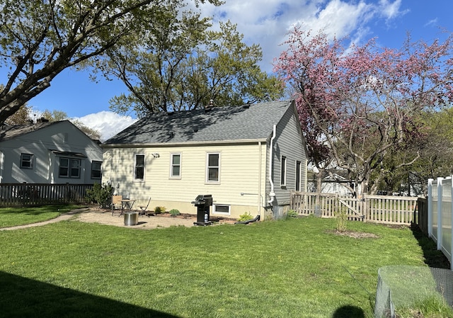 back of property with a fenced backyard, a yard, a patio, and roof with shingles