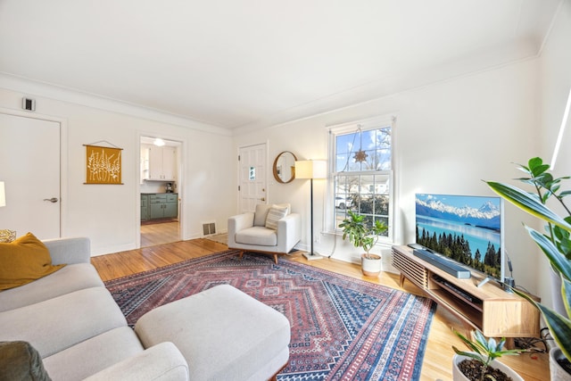 living room with visible vents, crown molding, baseboards, and wood finished floors