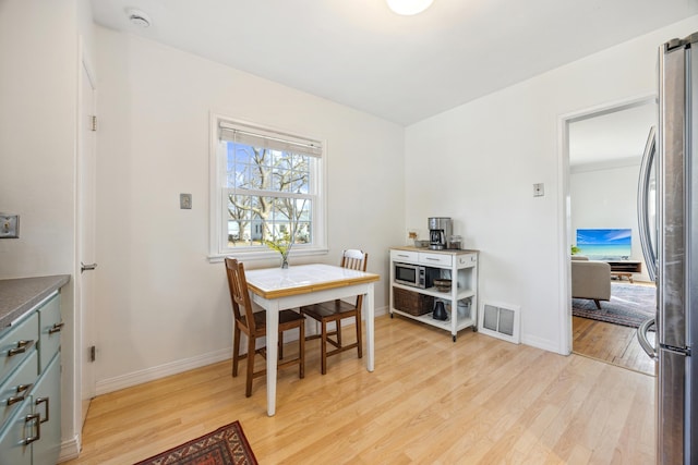 dining space featuring light wood-style flooring, visible vents, and baseboards