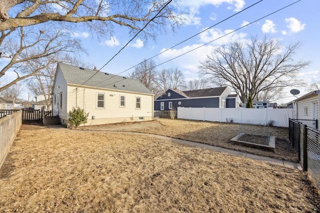 back of house with a fenced backyard and a shingled roof