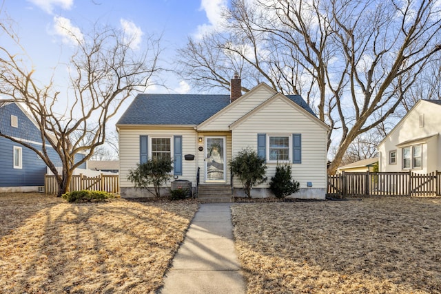 bungalow-style home featuring a shingled roof, a chimney, and fence