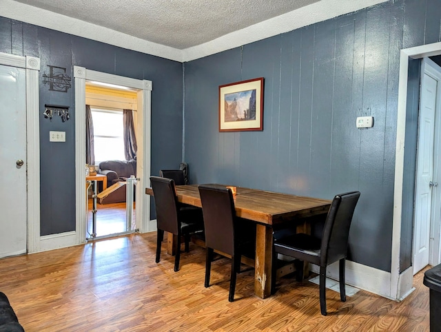 dining space featuring a textured ceiling, baseboards, and wood finished floors