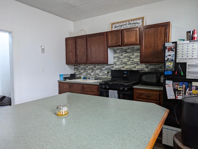 kitchen featuring a sink, black appliances, a textured ceiling, and backsplash