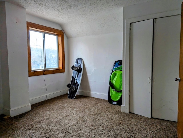 unfurnished bedroom with vaulted ceiling, a textured ceiling, and carpet flooring