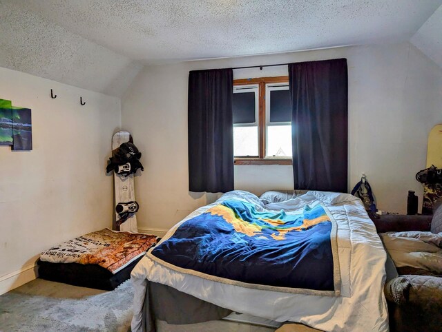 bedroom featuring lofted ceiling, a textured ceiling, and baseboards