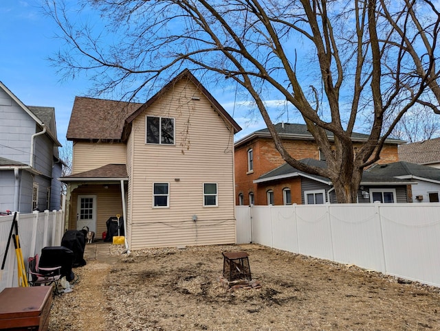 back of house featuring a fire pit, a shingled roof, and a fenced backyard