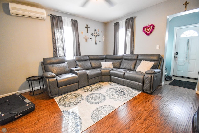 living area featuring plenty of natural light, an AC wall unit, and wood finished floors