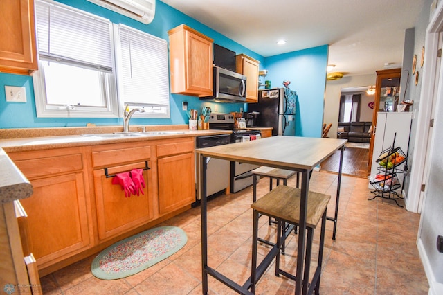 kitchen with appliances with stainless steel finishes, light countertops, a sink, and light tile patterned flooring