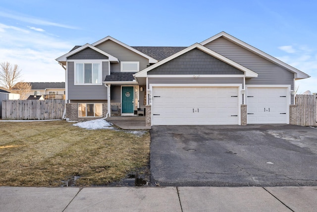 view of front facade with aphalt driveway, a front yard, fence, and a garage