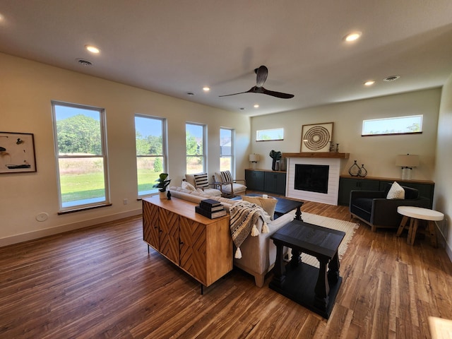 living room with recessed lighting, dark wood-style flooring, a brick fireplace, and baseboards