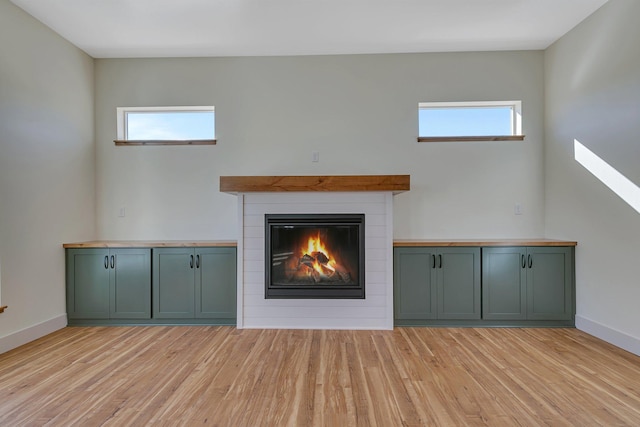 6624 Captains Cir NW, Sauk Rapids, MN 56379 - unfurnished living room with light wood-type flooring, a glass covered fireplace, and baseboards