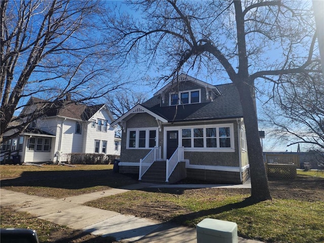 view of front of property featuring a front lawn and roof with shingles