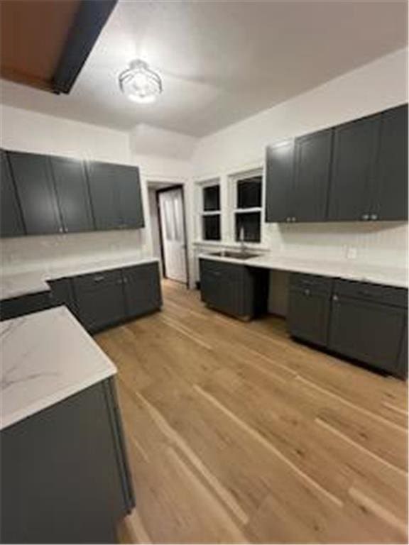 kitchen with light wood-style floors, light countertops, dark cabinets, and built in study area