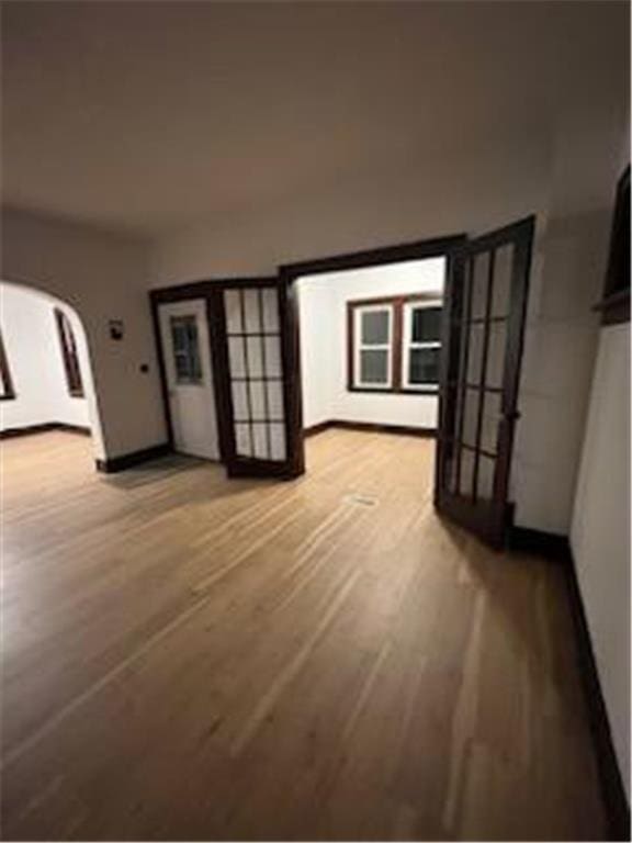 interior space with baseboards, arched walkways, and wood finished floors