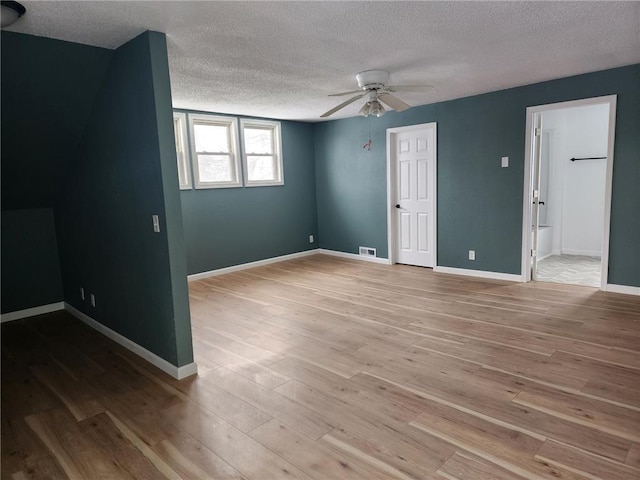 interior space with visible vents, a textured ceiling, baseboards, and wood finished floors