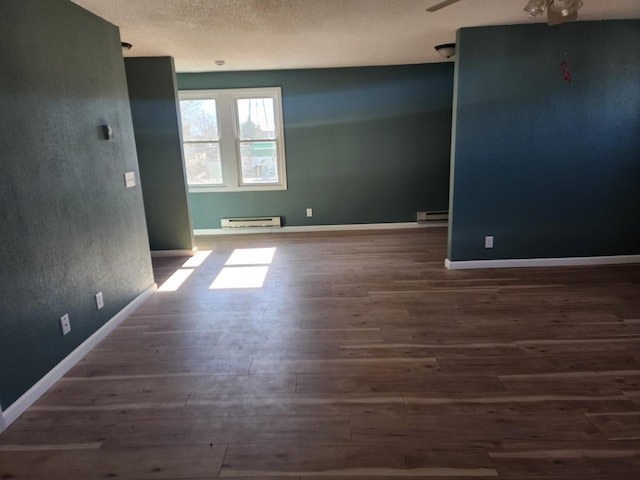 empty room with a baseboard radiator, baseboards, and wood finished floors