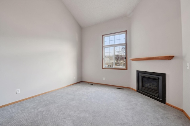 unfurnished living room with carpet floors, lofted ceiling, visible vents, a glass covered fireplace, and baseboards