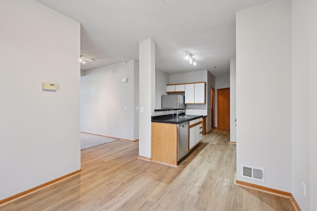 kitchen featuring stainless steel appliances, visible vents, light wood-style floors, white cabinetry, and baseboards