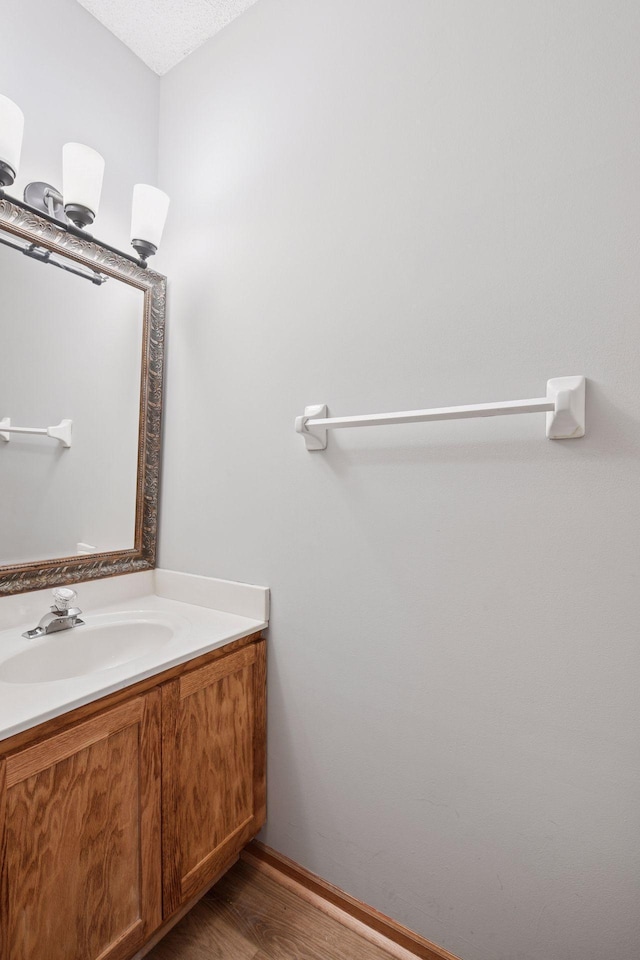 bathroom featuring a textured ceiling, wood finished floors, vanity, and baseboards