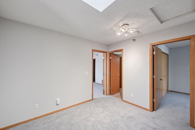 carpeted empty room featuring a textured ceiling and baseboards