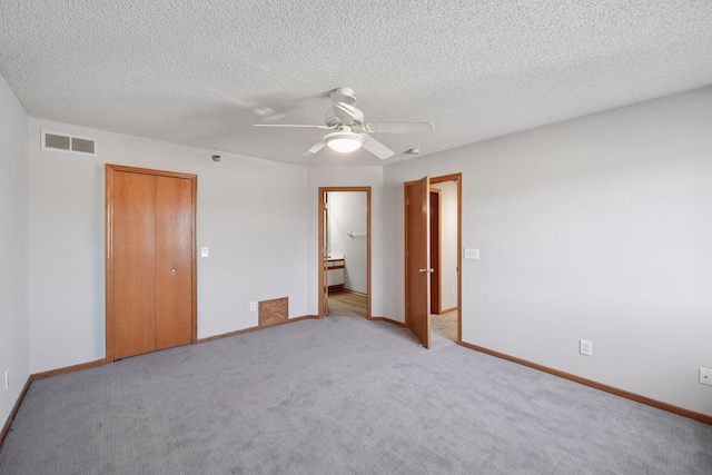 unfurnished bedroom featuring baseboards, visible vents, a textured ceiling, and light colored carpet