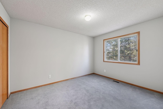 empty room featuring visible vents, baseboards, and carpet flooring