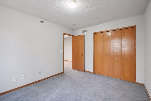 unfurnished bedroom featuring baseboards, visible vents, carpet, a textured ceiling, and a closet